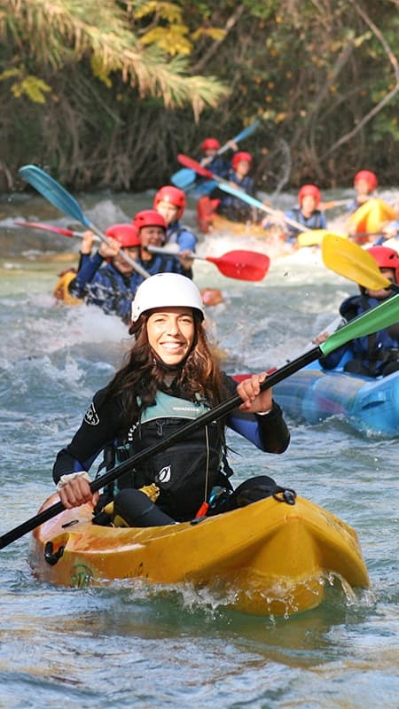 Kayakista navegando en un open kayak individual por las aguas turquesas del río Cabriel entre paredes de roca.