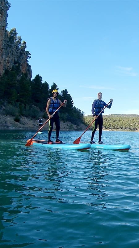 Group of people with a guide practicing paddle surf in the crystal-clear waters of the Cabriel River.