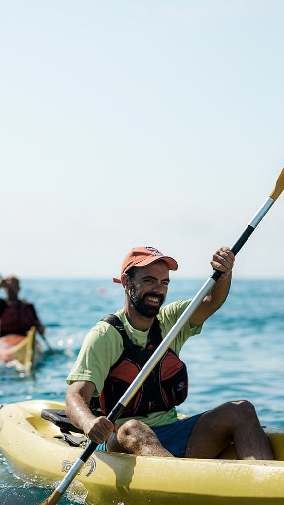 Couple paddling a rented kayak through the crystal-clear waters of the Vilanova i la Geltrú coast.